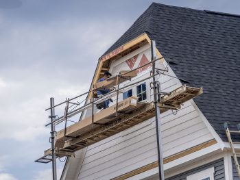 Carpenter On Scaffolding Installing White Vinyl Siding On A New Construction American Single Family Home In The Usa